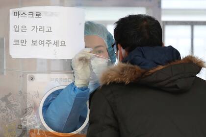 Una trabajadora médica, usando equipo protector, toma una muestra de un hombre en una instalación temporal de pruebas diagnósticas de coronavirus en Seúl, Corea del Sur, el sábado 4 de diciembre de 2021. (Park Mi-so/Newsis vía AP)