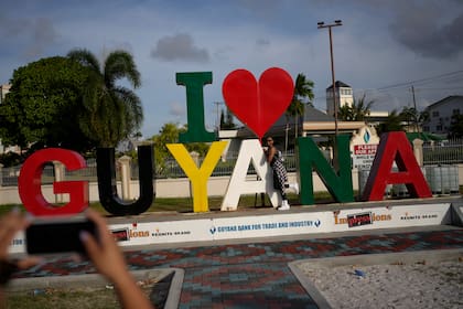 Una turista se fotografía frente a un cartel de bienvenida al país en Georgetown, la capital