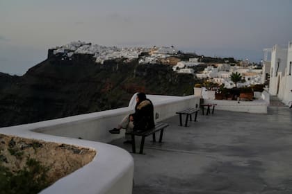 Una turista se sienta en Firostefani mientras las autoridades griegas toman medidas de emergencia en respuesta a la actividad sísmica en la popular isla turística griega de Santorini, en el mar Egeo, el lunes 3 de febrero de 2025