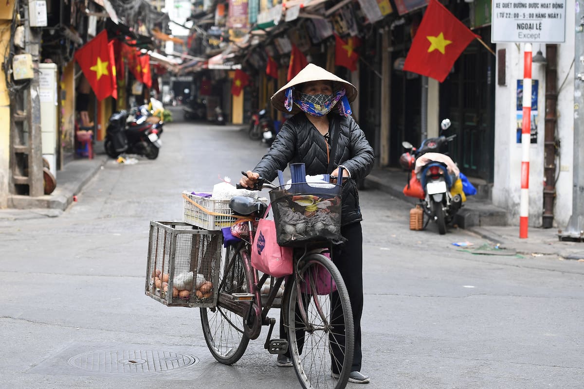 Una vendedora de huevos camina con su bicicleta cargada de mercancías a lo largo de una calle del distrito antiguo de Hanoi, en Vietnam, el 18 de febrero de 2021