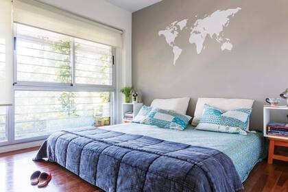 Una vez más, el esténcil con referencia viajera levanta el ambiente: sobre la pared gris, el mapamundi se luce como marco para la cama.