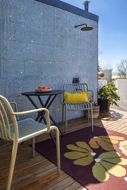 Una vieja parrilla y un lavaderito se demolieron para hacer esta terraza con deck y una pared de venecitas que aloja la ducha de exterior.