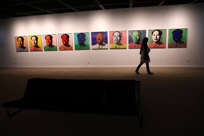 Una visitante pasa junto a una serie de retratos del difunto líder chino Mao Zedong realizada por Andy Warhol, el 19 de octubre de 2021 en el Museo de Arte Contemporáneo de Teherán. Los iraníes acudieron en masa al museo para maravillarse con la emblemática obra del artista pop estadounidense. (AP Foto/Vahid Salemi)