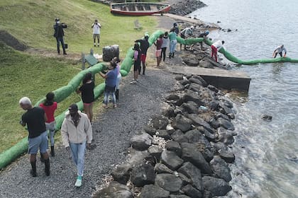 Una vista aérea muestra a los voluntarios que llevan la barrera hecha a mano para bloquear el petróleo filtrado del granelero MV Wakashio el 10 de agosto de 2020