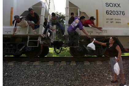 Una voluntaria de "Las Patronas" pasa comida y agua a los inmigrantes en el tren "La Bestia"en su camino a la frontera con la Estados Unidos