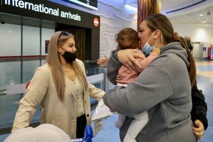 Unas familias se abrazan después de que un vuelo procedente de Los Ángeles llegara al aeropuerto internacional de Auckland al abrirse la frontera neozelandesa para los países con exención de visado el lunes 2 de mayo de 2022.