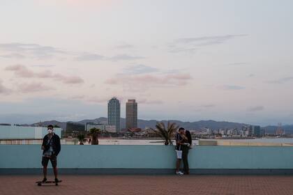 Unas pocas personas transitan por el paseo marítimo de la playa de la Barceloneta en Barcelona el 30 de mayo de 2020 mientras el país comienza a aflojar un cierre nacional para evitar la propagación del nuevo coronavirus