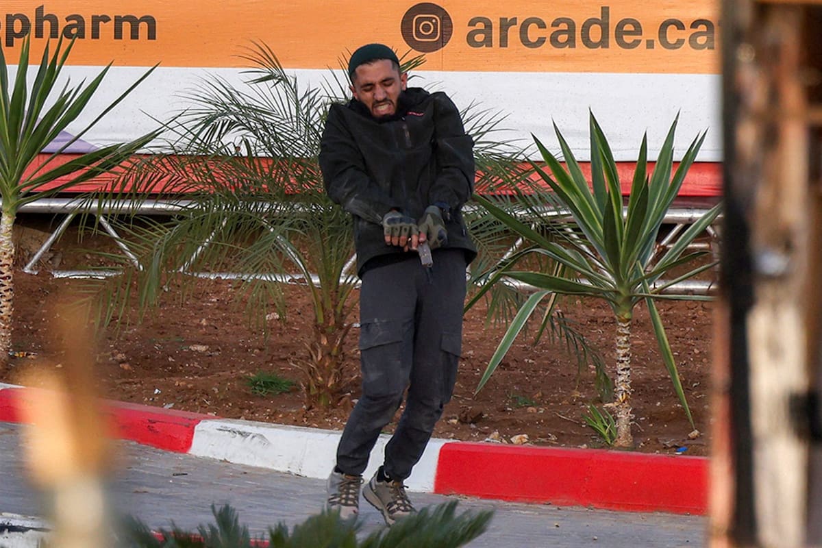 Uno de dos hombres palestinos armados carga su arma durante un intercambio de disparos con fuerzas israelíes en el puesto de control norte de Hebrón, en Cisjordania
