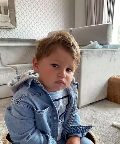 Uno de los hijos de la pareja en el living, donde la mayoría de los elementos son de tonalidades grises