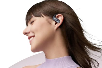 Unos auriculares TWS Shokz OpenFit Air; la bocina se ubica contra la oreja, pero deja entrar el sonido ambiente; tiene una patilla que va detrás de la oreja para que no se caigan