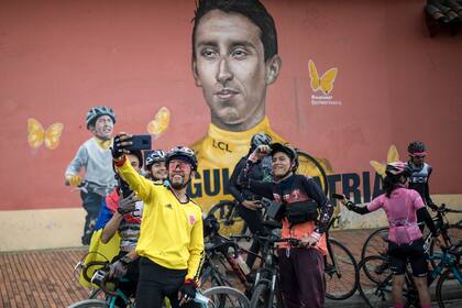 Unos ciclistas se reúnen frente a un mural del ciclista colombiano Egan Bernal en su ciudad natal de Zipaquirá, en Colombia, el domingo 30 de mayo de 2021. Bernal ganó el Giro de Italia el domingo en Milán. (AP Foto/Ivan Valencia)