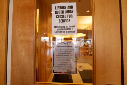 Unos letreros son colocados en las puertas de entrada para avisar a los visitantes que la biblioteca está cerrada debido a una contaminación de metanfetamina, el jueves 12 de enero de 2022, en Englewood, Colorado. (AP Foto/David Zalubowski)