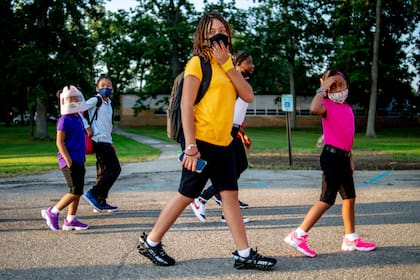 Unos niños llegan al primer día de escuela en la Primaria Freeman en Flint, Michigan, el 4 de agosto de 2021. (Jake May/The Flint Journal via AP)