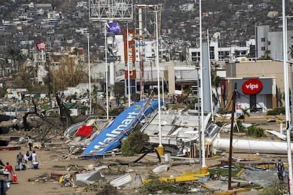 Unos residentes caminan junto a los escombros tras el paso del huracán Otis en Acapulco, México, el viernes 27 de octubre de 2023