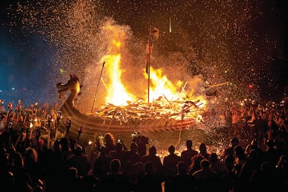 UP HELLY AA El último martes de enero la capital de las islas Shetland (entre las Feroe, Noruega y Gran Bretaña), Lerwick, celebra en llamas el fin de la temporada navideña. Más de mil guizers (personajes masculinos ataviados con una vestimenta especial) desfilan con antorchas y las lanzan sobre la réplica de un drakkar, típica embarcación vikinga con más de mil años de antigüedad. La celebración dura todo el día y se prolonga con música y bailes hasta el alba.