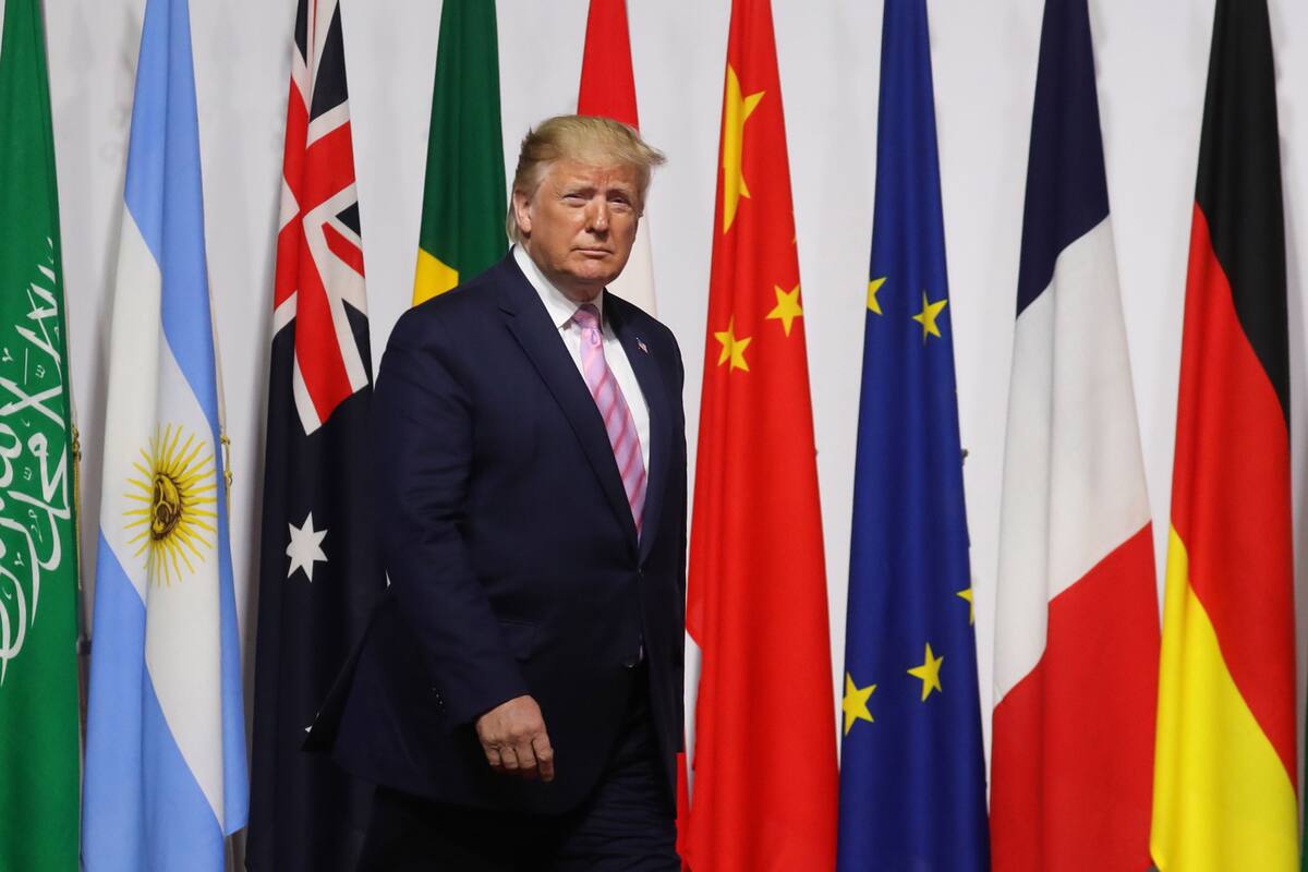 US President Donald Trump walks past G20 member flags as he is welcomed by Japanese Prime Minister Shinzo Abe prior to the family photo at the G20 Osaka Summit in Osaka on June 28, 2019. (Photo by Ludovic MARIN / POOL / AFP)