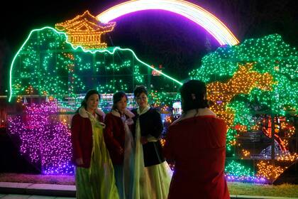 Varias mujeres se toman una foto durante un festival de luces en celebración del 110mo aniversario del natalicio del fallecido gobernante Kim Il Sun, en la plaza que lleva su nombre, el jueves 14 de abril de 2022, en Pyongyang, Corea del Norte. (AP Foto/Jon Chol Jin)