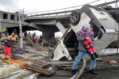 Varias personas cruzan por un puente improvisado para huir del suburbio de Irpín, cercano a Kiev, el lunes 7 de marzo de 2022, en Ucrania. (AP Foto/Efrem Lukatsky)