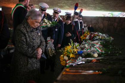 Varias personas depositan flores sobre las tumbas de las víctimas de la masacre de las Fosas Ardeatinas durante una ceremonia conmemorativa por su 80º aniversario, el viernes 22 de marzo de 2024, en Roma, Italia. En esta cueva se llevó a cabo la matanza de 335 civiles y presos políticos el 24 de marzo de 1944 a manos de soldados nazis. (Foto AP/Andrew Medichini)
