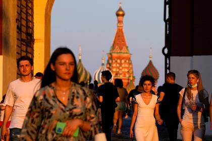 Varias personas, en su mayoría sin mascarilla, caminan por la Plaza Roja al atardecer, en Moscú, Rusia, el 24 de junio de 2021. (AP Foto/Alexander Zemlianichenko)