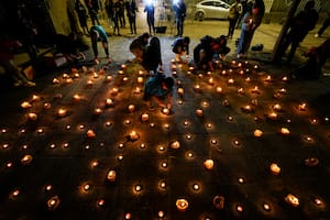 Varias personas encienden velas durante una vigilia frente a la sede de los Carabineros en honor de tres policías asesinados en el sur de Chile