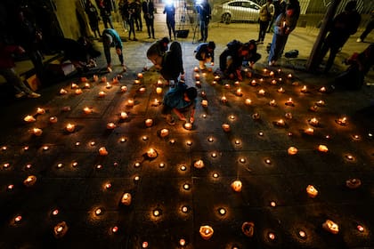 Varias personas encienden velas durante una vigilia frente a la sede de los Carabineros en honor de tres policías asesinados en el sur de Chile