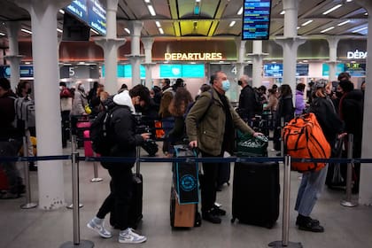 Varias personas hacen fila en la Estación Internacional St. Pancras, la terminal del tren Eurostar para viajar a Francia y otros países del continente europeo, el viernes 17 de diciembre de 2021 en Londres. (AP Foto/Matt Dunham)