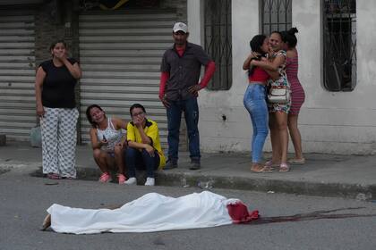 Varias personas lloran junto al cadáver de un hombre, asesinado en circunstancias desconocidas, en una calle de Durán, Ecuador, el 21 de julio de 2023, en medio de una ola de violencia que las autoridades atribuyen a la lucha de territorio entre bandas del crimen organizado. (AP Foto/Dolores Ochoa)