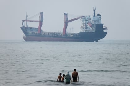 Varias personas observan desde la orilla mientras un buque parece fondeado en el estrecho de Ormuz, ante la costa de Bandar Abbas, Irán, el 30 de junio de 2026.