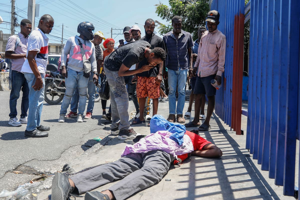Varias personas observan el cuerpo de un hombre tendido en la calle del barrio de Delmas 30 en Puerto Príncipe, Haití, el lunes 1 de abril de 2024