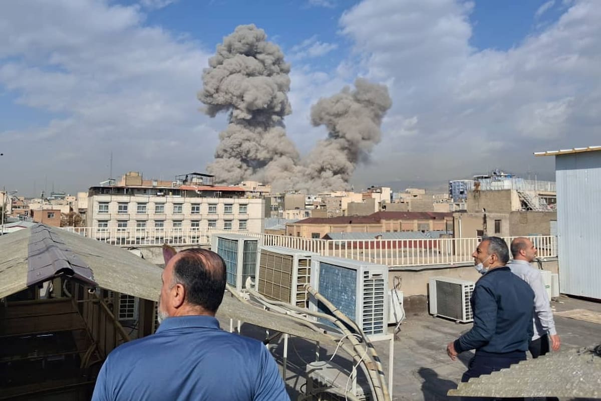 Varias personas observan mientras una columna de humo señala el lugar donde se produjo una explosión en Teherán, Irán, el 28 de febrero de 2026. (AP Foto)