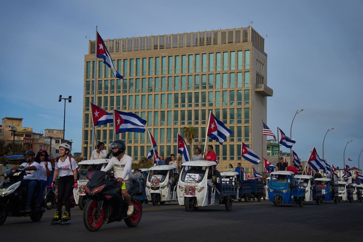 Varias personas pasan en vehículos eléctricos frente a la embajada de Estados Unidos durante una marcha juvenil antiimperialista organizada por el gobierno en La Habana