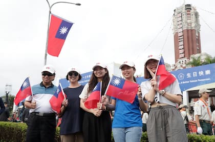 Varias personas posan con banderas taiwanesas durante las celebraciones del Día Nacional frente al edificio presidencial en Taipéi, Taiwán, el jueves 10 de octubre de 2024.