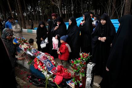 Varias personas rezan frente a los ataúdes de las víctimas de un ataque suicida durante su funeral en la ciudad de Kermán, Irán, el viernes 5 de enero de 2024. (AP Foto/Vahid Salemi)