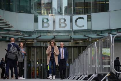 Varias personas salen de la sede de la BBC en Londres, el martes 18 de octubre de 2022, día en que la emisora ha cumplido 100 años de servicio. (AP Foto/Kin Cheung)