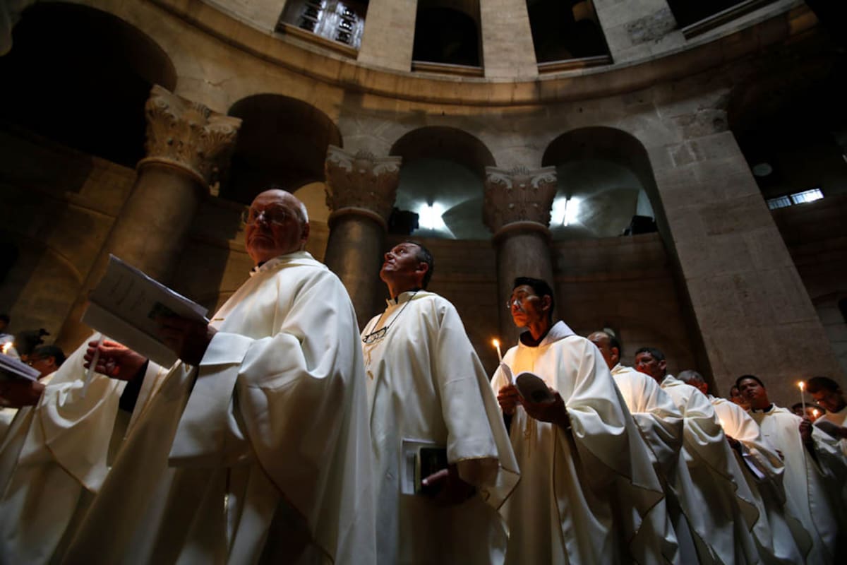 Varios católicos sostienen velas en la Iglesia del Santo Sepulcro en la Ciudad Vieja de Jerusalén por las celebraciones de Semana Santa.