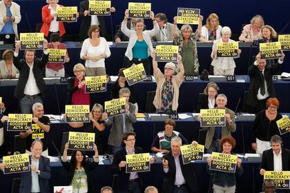 Varios diputados del Parlamento Europeo muestran pancartas que dicen Hola Democracia, Adiós ACTA