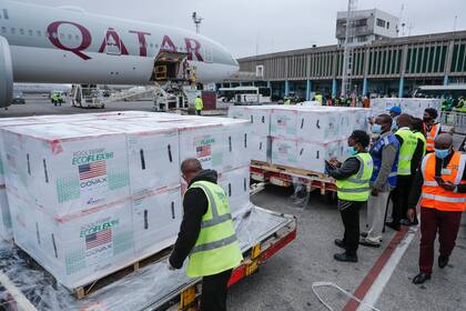 Varios funcionarios reciben cajas de la vacuna de Moderna contra el coronavirus después de su llegada al aeropuerto de Nairobi, Kenia, el lunes 6 de septiembre de 2021. Las dosis son parte de las vacunas donadas por Estados Unidos a través del programa COVAX. (AP Foto/Brian Inganga)