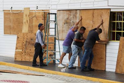 Varios hombres trabajan para proteger una casa antes de la llegada del huracán