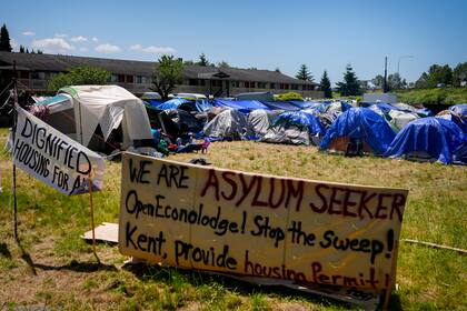 Varios letreros que piden ayuda se encuentran frente a un campamento de solicitantes de asilo provenientes en su mayoría de Venezuela, Congo y Angola, junto a un motel desocupado propiedad del condado, el miércoles 5 de junio de 2024 en Washington