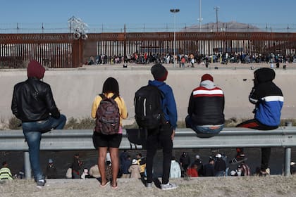 Varios migrantes observan a otros junto a la valla fronteriza en Ciudad Juárez, México, el 21 de diciembre de 2022, al otro lado de El Paso, Texas. (AP Foto/Christian Chávez, archivo)