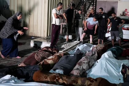 Varios palestinos lloran por sus familiares muertos por un bombardeo israelí contra una escuela de la ONU en el campamento de refugiados de Nusseirat (AP Foto/Abdel Kareem Hana)