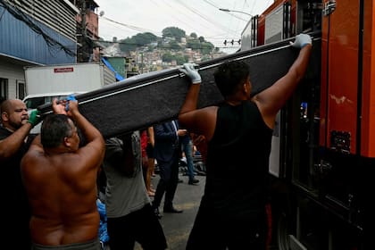 Vecinos cargan un cadáver en un camión morgue en la plaza São Lucas de la favela Vila Cruzeiro, en el complejo Penha
