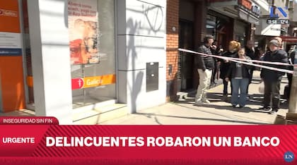 Vecinos observan el trabajo de la policía tras el asalto al Banco Galicia de Lomas del Mirador