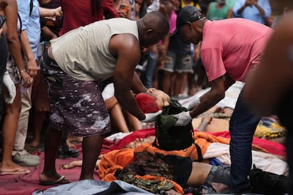 Vecinos vuelven a colocar una cabeza dentro de una bolsa después de exhibirla brevemente, en la favela del Complexo da Penha, en Río de Janeiro, Brasil