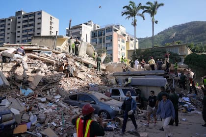Vecinos y rescatistas buscan entre los escombros de un edificio que colapsó durante un terremoto en Caracas