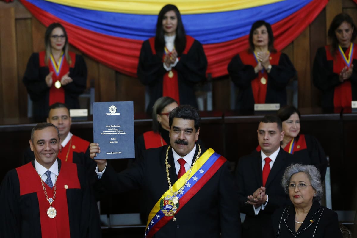 Venezuelan President Nicolas Maduro holds up a book related to his swearing-in ceremony at the Supreme Court in Caracas, Venezuela, Thursday, Jan. 10, 2019. Maduro was sworn in to a second term amid international calls for him to step down and a devastating economic crisis. (AP Photo/Ariana Cubillos