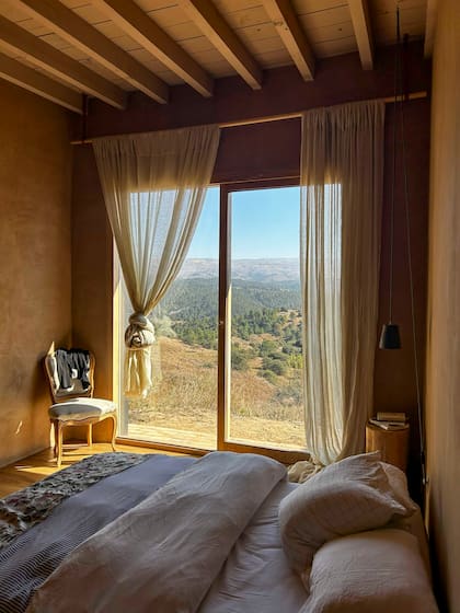 Ventanales con carpinterías de madera y cortinas traslúcidas para que nada interrumpa las vistas desde el dormitorio