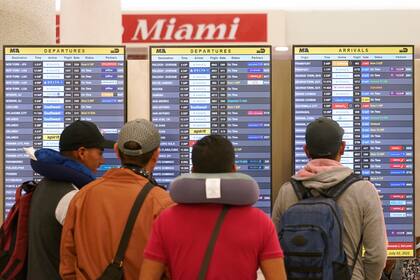 Viajeros buscan sus vuelos en el Aeropuerto Internacional de Miami. (AP Foto/Marta Lavandier)