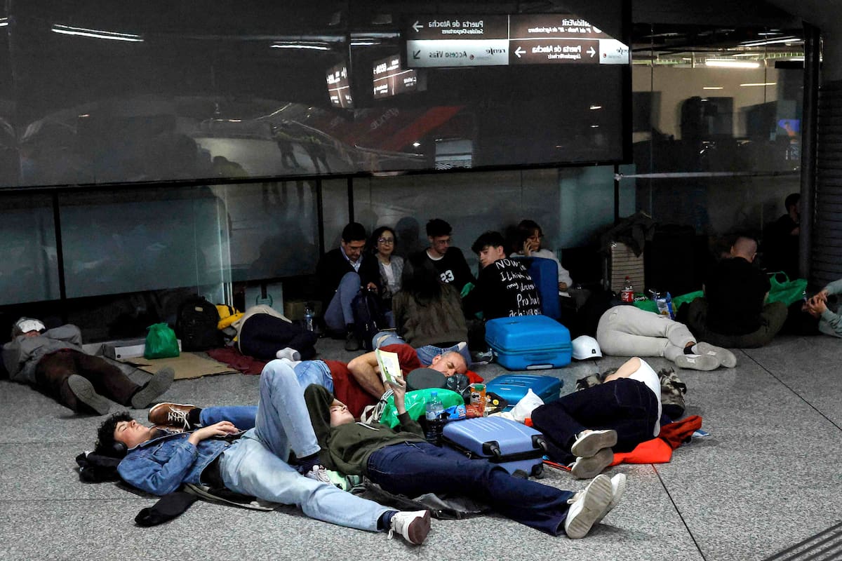Viajeros yacen en el suelo mientras se preparan para pasar la noche en la estación de tren de Atocha, tras el corte de luz masivo que afectó a España y el sur de Francia el 28 de abril